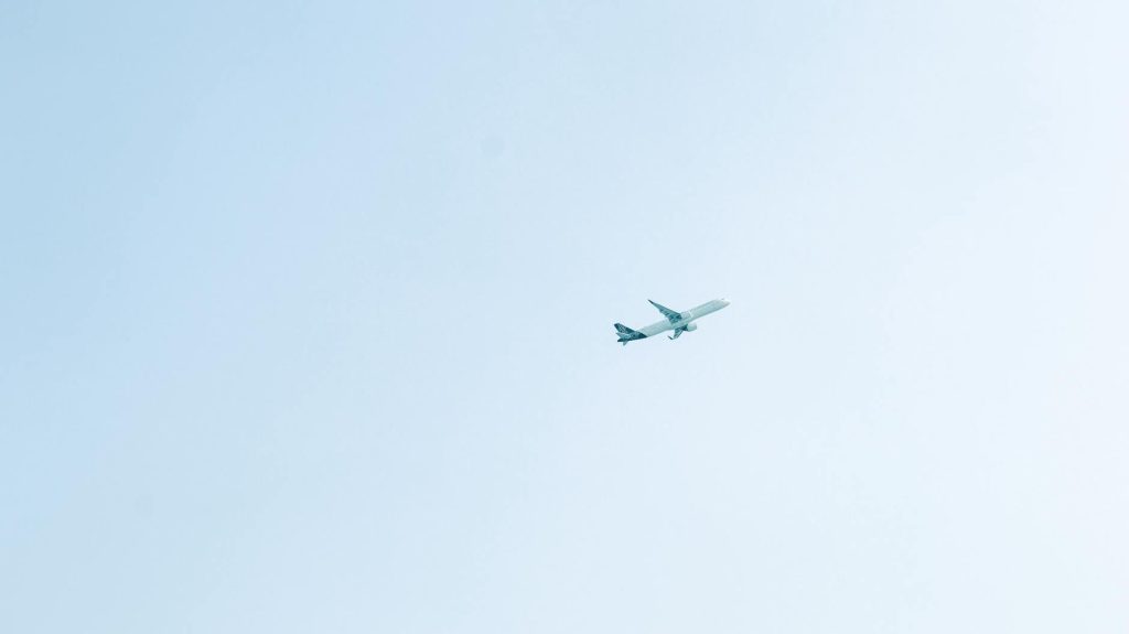 Um avião de passageiros voa por um céu azul e límpido, transmitindo a sensação de viagem e liberdade.